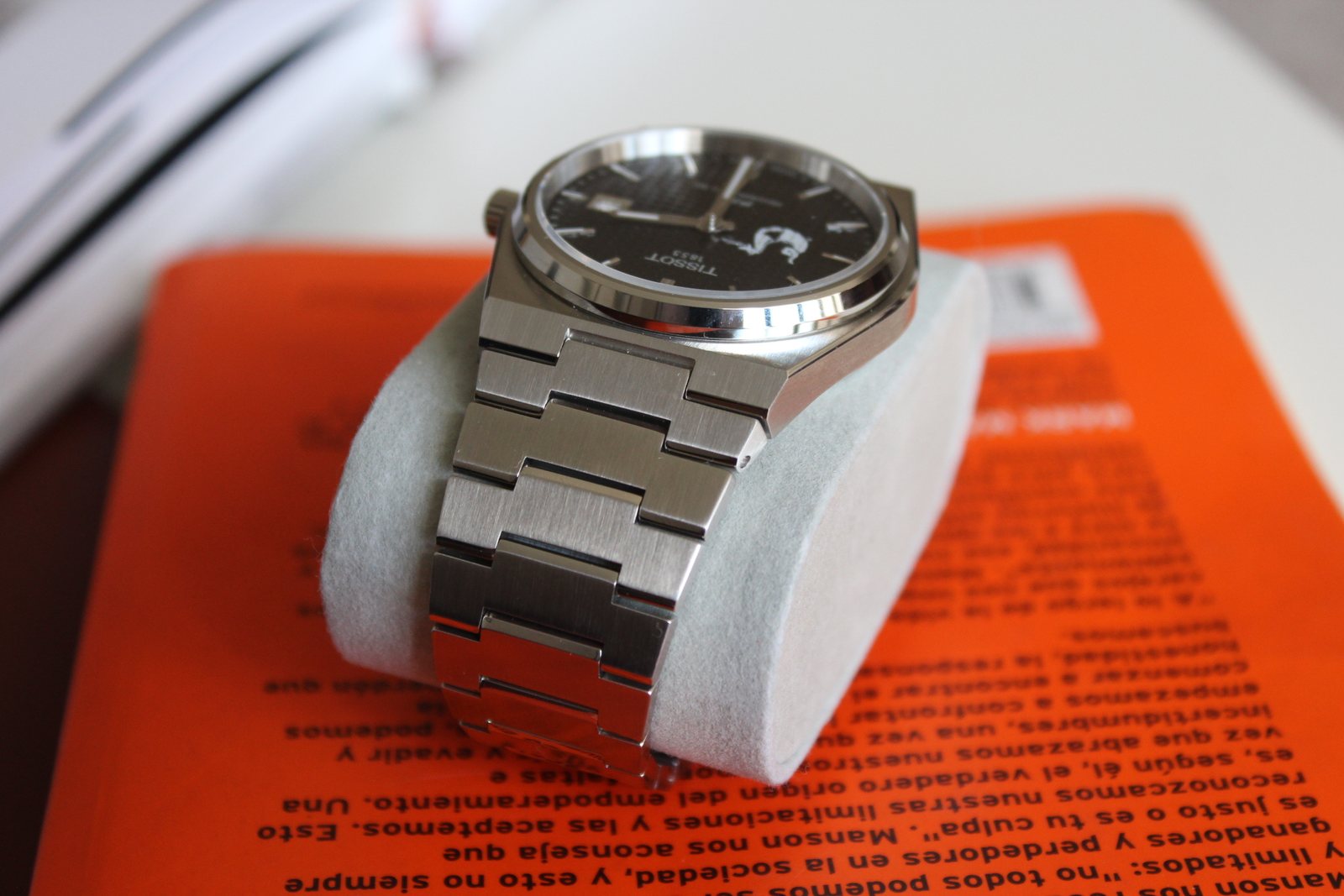Reloj Tissot de carátula negra sobre un cojín, con el logotipo del cliente impreso en la esfera.