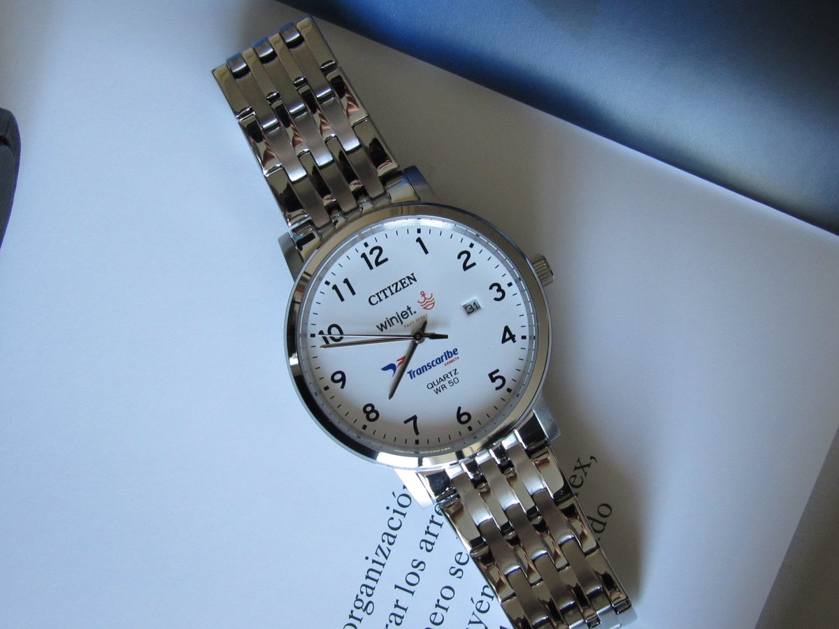 Carátula blanca de un reloj Citizen con los logotipos «winjet. fast ferry» y «Transcaribe conecta» impresos bajo la marca.