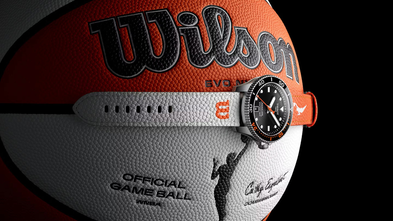 Reloj Tissot Seastar con correa de tela naranja y blanca sujeto sobre un balón oficial de la WNBA de Wilson.
